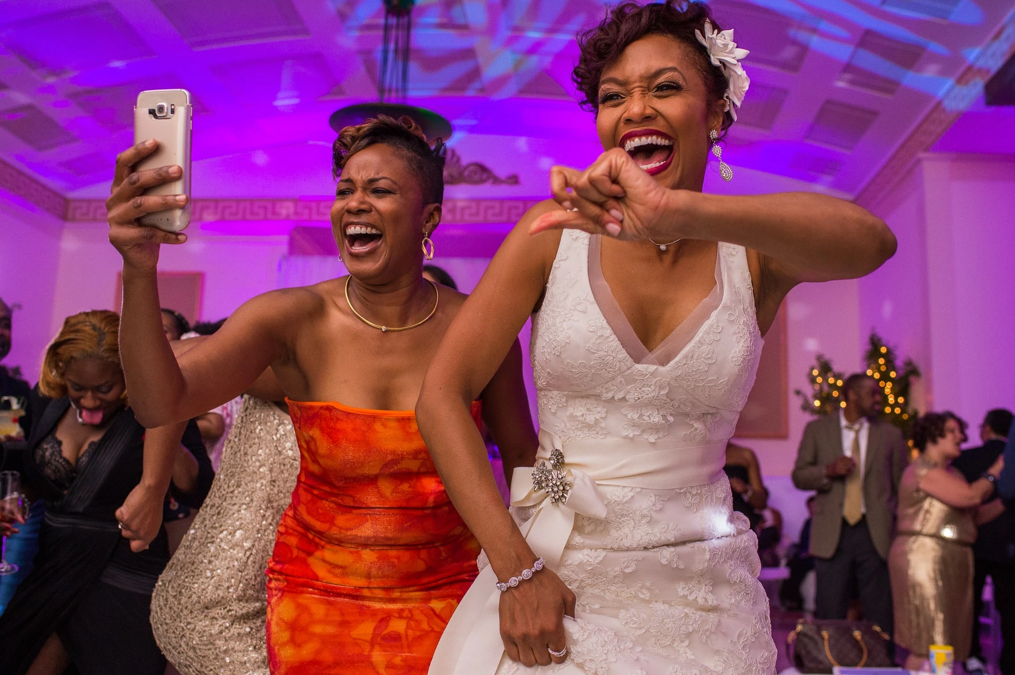Bride and guest laughing and dancing under purple lighting
