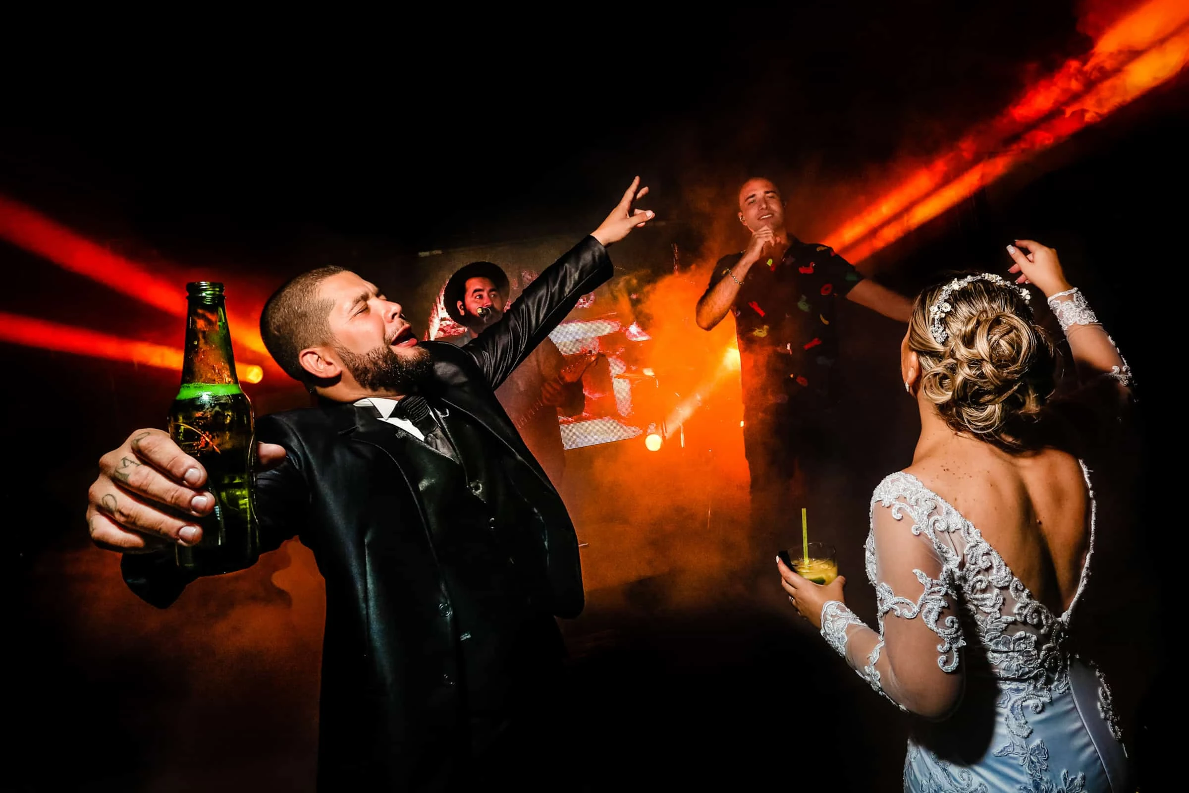 Wedding guests celebrating under warm red dance-floor lighting