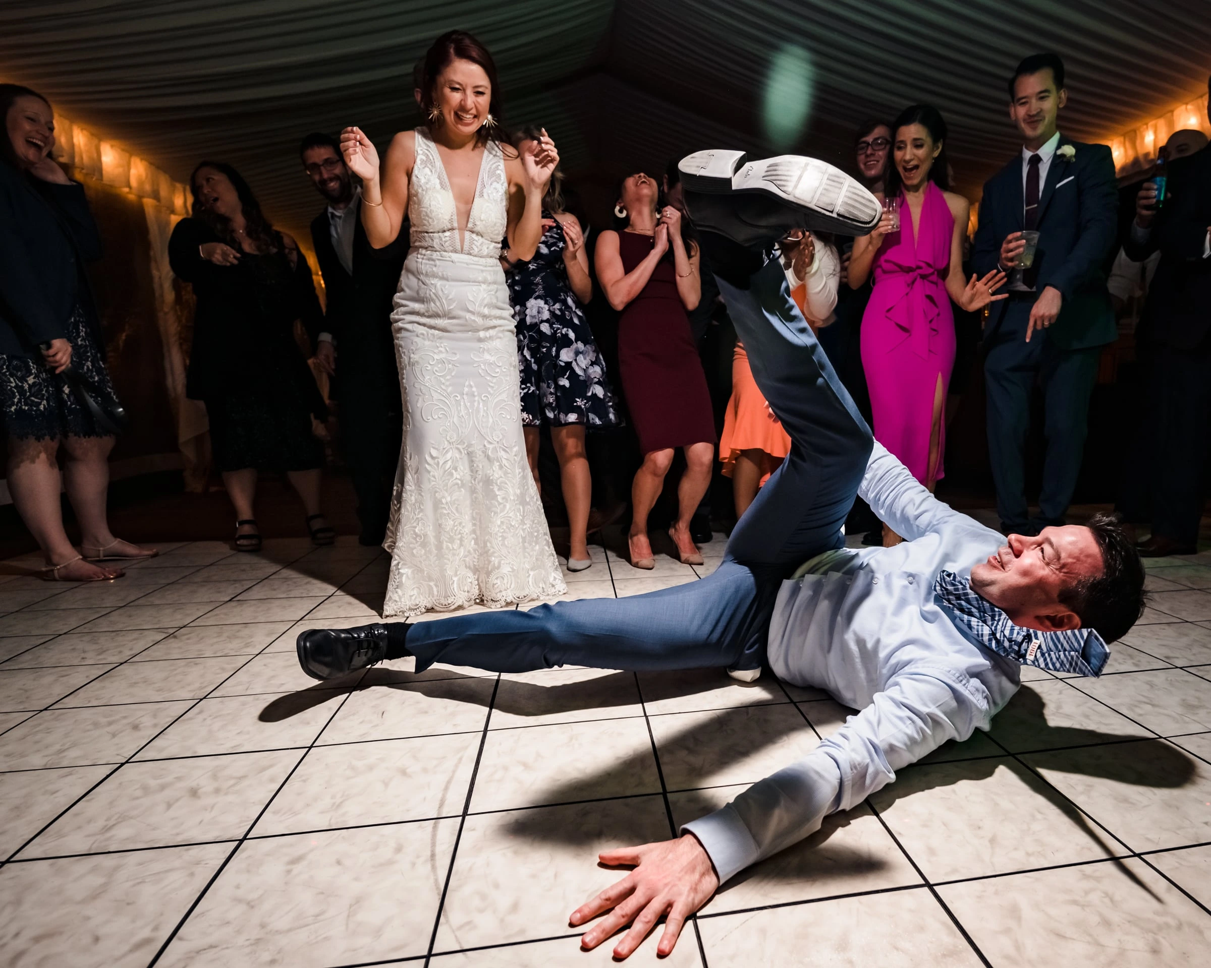 A guest showing off a dance move as the bride and friends watch